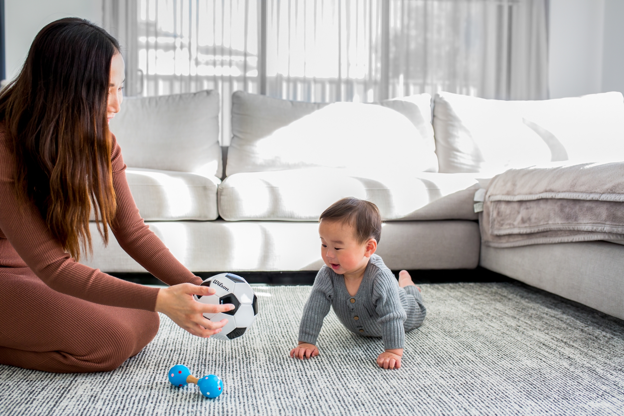 Mother playing with a ball to distract her colic baby