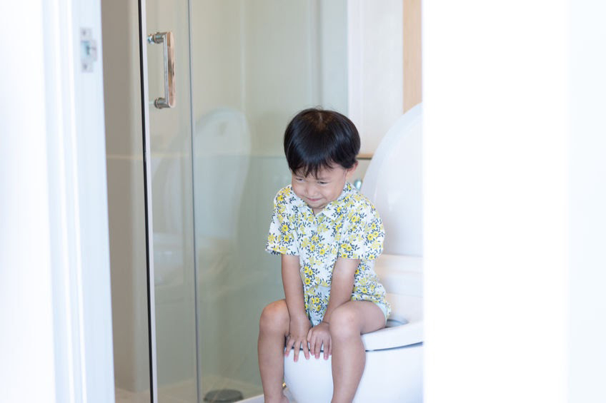 Baby poop colour: Child seated on toilet